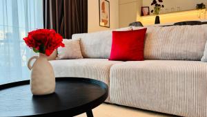 Your Home in Bucharest - Premium 1BR Apartments in ONE Cotroceni في بوخارست: مزهرية مع الورود الحمراء على طاولة في غرفة المعيشة