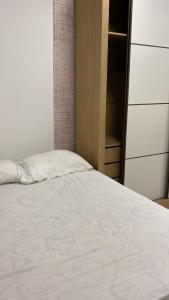 a bedroom with a white bed and a closet at Itaipuaçu Central in Maricá