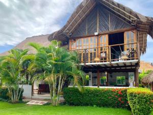 a house with a thatched roof and palm trees at CasaBella Cabaña con Piscina Palomino in Palomino