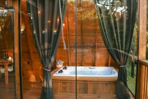 a bath tub in a wooden house with curtains at Reserva Linha Bonita - Chalés Românticos in Gramado