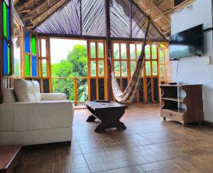 a living room with a couch and a tv and a hammock at CasaBella Cabaña con Piscina Palomino in Palomino