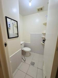 ein weißes Badezimmer mit Toilette und Spiegel in der Unterkunft JJMC HOMESTAY 29 with Netflix and Wifi in Manila