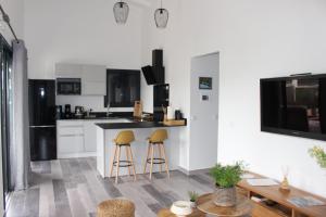 a kitchen with two bar stools and a counter at Kaza Kigélia - Villa avec piscine privative - Proche de Tout in Grand-Bourg