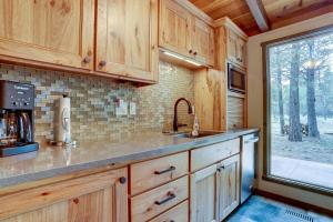 a kitchen with wooden cabinets and a sink and a window at Sunriver Escape Sleeps 8 Pet Friendly SHARC Hot Tub in Bend