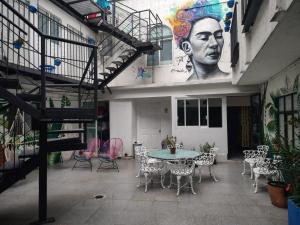 a patio with a table and chairs and a mural at HERMILA Tlalpan in Mexico City