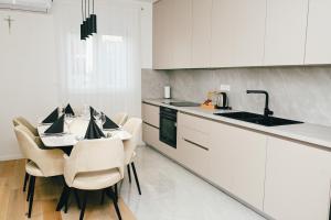 a kitchen with white cabinets and a table and chairs at Apartman Royal in Posušje