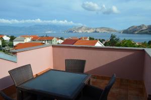a table and chairs on a balcony with a view of the water at Apartments & Rooms Nensi in Baška