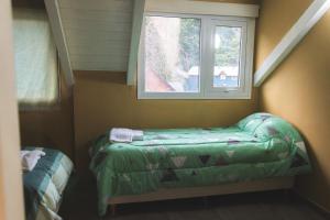 Cette petite chambre dispose d'une fenêtre et d'un lit vert. dans l'établissement Apart BANDURRIAS I - a 200ms del Lago Lacar, à San Martín de los Andes