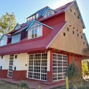 a large red house with a gambrel roof at Habitación doble con baño y vista a la montaña in San Pablo Etla