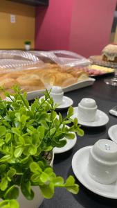 a table with white plates and a plant on it at Domus Hotel Rio Verde - Parauapebas in Parauapebas