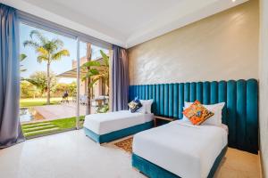 two beds in a room with a large window at Dar ilyan in Marrakech