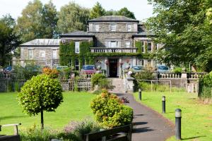 an old house with a garden in front of it at Windermere Manor Hotel in Windermere