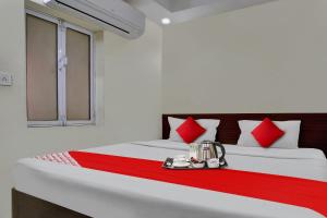 a bedroom with a bed with red and white pillows at Hotel O Arjun in Prayagraj