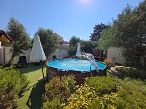 a swimming pool with an umbrella in a yard at Apartments PHARIA in Jelsa