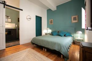 1 dormitorio con 1 cama con paredes azules y suelo de madera en La Luciole, en Périgueux