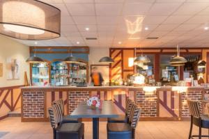 ein Restaurant mit Tisch und Stühlen und einer Bar in der Unterkunft Charmant cottage dans Village Normandy Garden, Pierre & Vacances in Branville