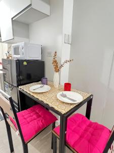 サンフェルナンドにあるAzure North Most Affordable Studio Staycation Suiteのピンクの椅子2脚とテーブルのあるキッチン