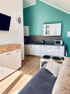 a kitchen with white cabinets and a couch in a room at Domki na Rozanej in Rowy +16 photos