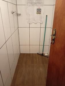 a bathroom with a shower with a mop on the wall at Chale de madeira com cozinha Refúgio das borboletas in Itatiaia