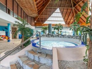 ein großer Whirlpool in einem Gebäude mit Palmen in der Unterkunft Charmant cottage dans Village Normandy Garden, Pierre & Vacances in Branville