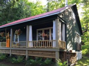 a small house with a large porch and a deck at Spa & Water access - Pionnier in Mont-Tremblant
