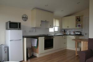 a kitchen with white cabinets and a white refrigerator at Castaway Cabin in St Merryn +17 photos