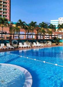 a large swimming pool with white chairs and palm trees at apartement cempaka mas in Jakarta