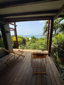 a porch with two chairs and a view of the ocean at Le lodge des raisiniers in La Trinité