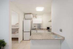 a white kitchen with a refrigerator and a sink at Apartaments Puig cardener 1 in Manresa