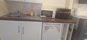 a kitchen counter with a sink and a microwave at Cosy Studio - Maisonette in a quite neighbourhhod can sleep 2 with private entrance and gate in Broadheath