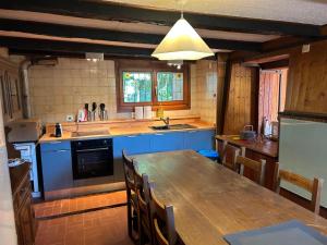 a large kitchen with a wooden table and blue cabinets at Ara Gesa Old Cottage in Curtina