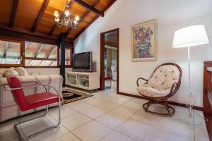 a living room with a chair and a television at Casa Fauna e Flora, muito verde e paz no Cuiabá in Petrópolis