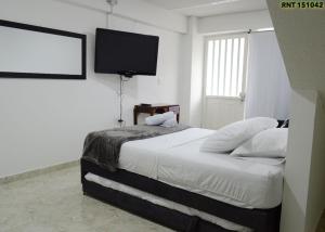 a bedroom with a bed and a flat screen tv at Mi pequeño hostal in Santa Rosa de Cabal