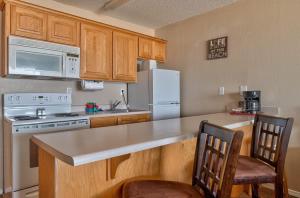 a kitchen with wooden cabinets and a white refrigerator at Comfy Second Floor Beachfront Condo - Sleeps 4 - Pool and Sauna in Lincoln City +29 photos
