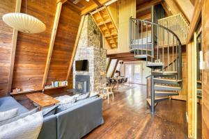a living room with a stone fireplace and a staircase at Modern A-Frame Cabin in the Woods in Rhododendron