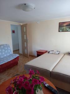 een woonkamer met 2 bedden en een tafel met bloemen bij Dom Hermana in Mrzeżyno