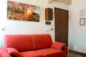 a red couch in a living room with a painting on the wall at B&B sa' GRAVIN in Castellaneta