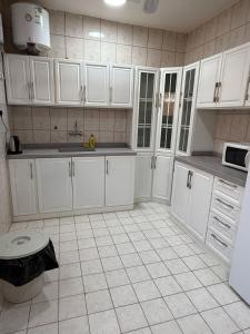 a kitchen with white cabinets and a tiled floor at شقة خالد المفروشة in Quai