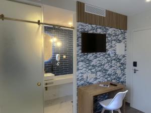 a bathroom with a sink and a television on a wall at Na Crista da Onda in Nazaré