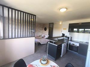 una cucina e un soggiorno con un tavolo e un letto di LeRelaisdOdile - Idéal PRO & Couple - Studio Cosy - Proche Metro - Parking Gratuit - Mons-en-Barœul - - WIFI HD - Smart TV - Entrée Autonome a Mons-en-Baroeul Altre 12 foto