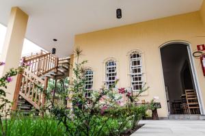 a building with a staircase and flowers in front of it at Pousada Canto da Praça in Bertioga