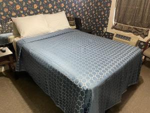 a bed in a room with a blue comforter at Delux Inn in Big Spring +2 photos