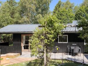 a black house with a patio and a table at 6 person holiday home in Brovst-By Traum in Brovst