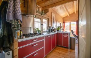 a large kitchen with red cabinets and windows at 1 Bedroom Stunning Home In Menaam in Dronrijp