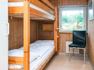 a bedroom with a bunk bed and a chair and a window at 5 person holiday home in Henne in Henne Strand