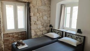 a black bed in a room with two windows at Roko's in Hvar