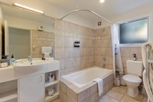 a bathroom with a tub and a sink and a toilet at Queenstown House Bed & Breakfast and Apartments in Queenstown +64 photos