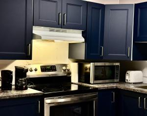 a kitchen with blue cabinets and a stove and microwave at Royal Oak Inn in Toronto
