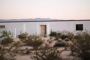 un edificio blanco en el desierto con montañas en el fondo en SkyDweller - Joshua Tree Modern, en Joshua Tree
