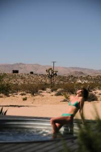 una mujer en bikini sentada en un charco de agua en SkyDweller - Joshua Tree Modern, en Joshua Tree